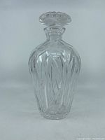 Front view of old cut crystal decanter with intricate cut lines and etched plant stems.