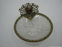 Full top view of the oval glass dish showing embossed bird designs, brass trim, and the ceramic topped brass adornment with pastoral scene.
