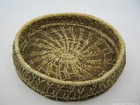 Top-down photo showing the detailed spiral weaving pattern inside the round pine needle basket with natural tan and brown fibers and tightly bound rim.