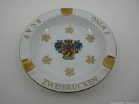 Top view of white porcelain ashtray with gold trim and RCAF 3 Wing Zweibrucken text and emblem in center.