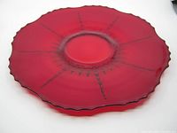 Top view of the vintage red ruby glass cake plate showing scalloped edges and embossed radiating design from center.