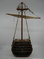 Front view of the wooden ship model cross-section showing the mast, sail boom, and some rigging with visible damage and wear.