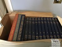 Box of books showing 12 volumes of My Book House by Olive Beaupré Miller with navy blue covers and gold lettering, plus other children's books including 'Tales Told in Holland', 'Nursery Friends From France', and 'Little Pictures of Japan'.