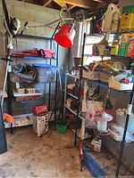 Two black metal wire shelving units seen from a distance in a basement with various stored items on them. Shelving units are tall and constructed from metal rods with wire grid shelves.
