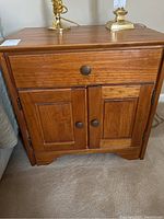 Front view of the wooden nightstand showing single drawer and two-door cabinet.