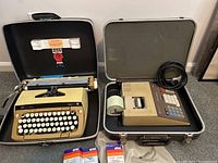Opened case showing Smith Corona Galaxie Twelve typewriter on left and Rockwell electric adding machine on right, both with cases and accessories.