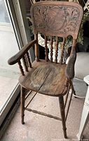 Full view of antique wooden high chair showing overall structure, seat, armrests, and legs with noticeable wear and vintage finish.