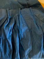 Top section of blue drapery panel showing pinch pleat heading and textured fabric.