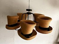 Chandelier from angled front showing four straw top hat shades and black metal frame