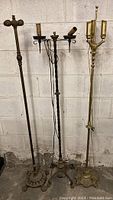 Three vintage metal floor lamps against a concrete wall showing their full height and bases