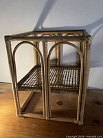 Full view of rattan side table showing square frame, woven shelf, and open top.