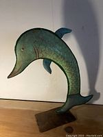 Full view of the metal fish art piece with curved body on metal base against white background.