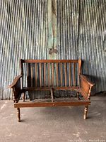 Front view of vintage wooden two-seat settee frame without cushions, showing solid overall structure with some wear
