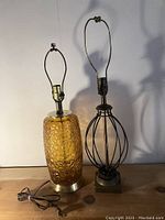 Two vintage table lamps side by side, amber glass lamp on the left and metal cage lamp on the right