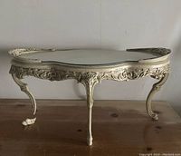 Full front view of ornate carved wood coffee table with glass top and detached leg piece visible