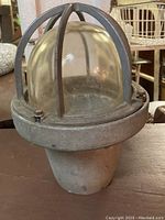 Front view of the vintage Killark HG-200 metal industrial light fixture showing wear and protective cage over glass dome.