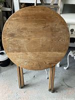 Top view of round solid oak table surface with natural wood grain and some wear marks.