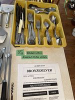 Yellow plastic cutlery tray filled with assorted metal forks, spoons, knives and butter knives