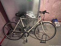 Side view of white Giant AFS Innov bicycle with helmet mounted and lock at front wheel