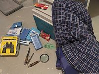 Full lot overview showing cooler, cooler blocks, sleeping bag, binoculars in box, magnifying glass, knife and fire starters.