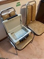 Photo showing two tan Corinthian vinyl padded kitchen chairs with chrome frames and the Sentry 1100 safe open on one chair, keys visible in lock.