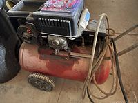 Used Craftsman air compressor with hose coiled on side, showing overall tank and wheels.