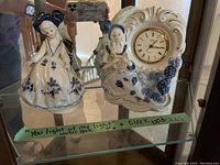 Two porcelain figurines, one functioning as a music box, the other a clock, both with blue floral detailing