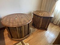 Round and hexagonal wooden end tables side by side showing wood grain tops and vertical slat sides with doors closed