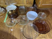 Photo showing an assortment of Pyrex bakeware and bowls, including amber glass covered casserole, clear rectangular and oval dishes, white mixing bowl, and various clear glass bowls.