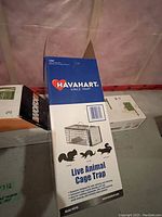 Havahart live animal cage trap box showing trap details for capturing small animals such as squirrels and chipmunks.