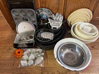 Overall shot showing full set of bakeware, mixing bowls, the Original Ove Glove, and multiple cookie cutters with bowls and pans stacked on a wooden floor.