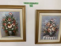 Pair of framed floral oil paintings each 18x24 inches with gold-tone frames and white mats, showing detailed flower arrangements in vases