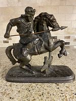 Front and left-side view of antique metal warrior on horse statue showing warrior holding spear and horse rearing.