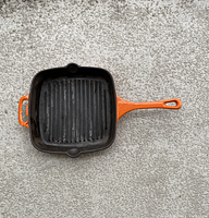 Top view showing black grill ridged interior surface and orange handle with hanging hole
