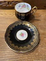 Top down view of Rosina cup and saucer showing floral and gold inlay details on black ceramic
