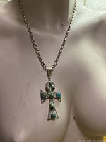 Full view of the silver necklace on a mannequin torso, showing the long chain and the ankh pendant with turquoise stones.