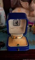 Blue leather Birks ring box open showing 14K gold band on tan velvet cushion