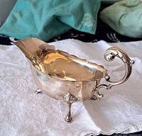 Three-quarter side view showing scalloped rim, scroll handle and one shell foot