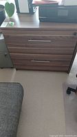 Closed view of the wood-finish two-drawer lateral file cabinet showing metal handles and lock.