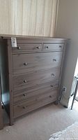 Front view of the dresser showing 5 drawers with black round knobs, wood grain visible in gray-brown finish.