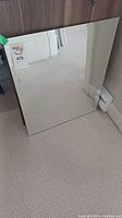 View of the full rectangular beveled edge mirror resting on carpet, showing the reflective surface and clean appearance.