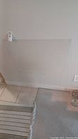 Clear plexiglass sheet standing against a wall on tile flooring, showing full sheet size and transparency.