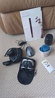 Overview of all items on carpet: speaker manual, binocular case, lens, headphones, mouse, containers, Mwazu box