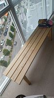 Wood bench near window, natural wood slats with light wood finish.