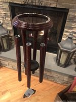 Photo showing the Corinthian Bells wind chimes hanging with visible textured reddish-brown chimes, circular top ring, and black cords, in front of a stone fireplace.