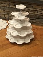 Photo of two assembled white plastic cupcake stands with four tiers, each tier has circular holders for cupcakes.