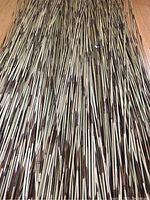 Close-up view showing numerous thin bamboo sticks with natural brown and tan stripes densely grouped together.