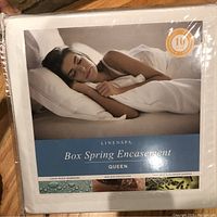 Photo of Linenspa box spring encasement mattress protector sealed in original packaging, showing brand name, product type, and queen size.
