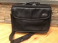 Front view of black Targus laptop briefcase showing front pocket with Targus logo and detachable shoulder strap.