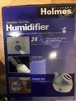 Photo of the front side of Holmes Ultrasonic Cool Mist Humidifier box showing key features such as 24 hour runtime, variable mist control, visible mist, compact size.